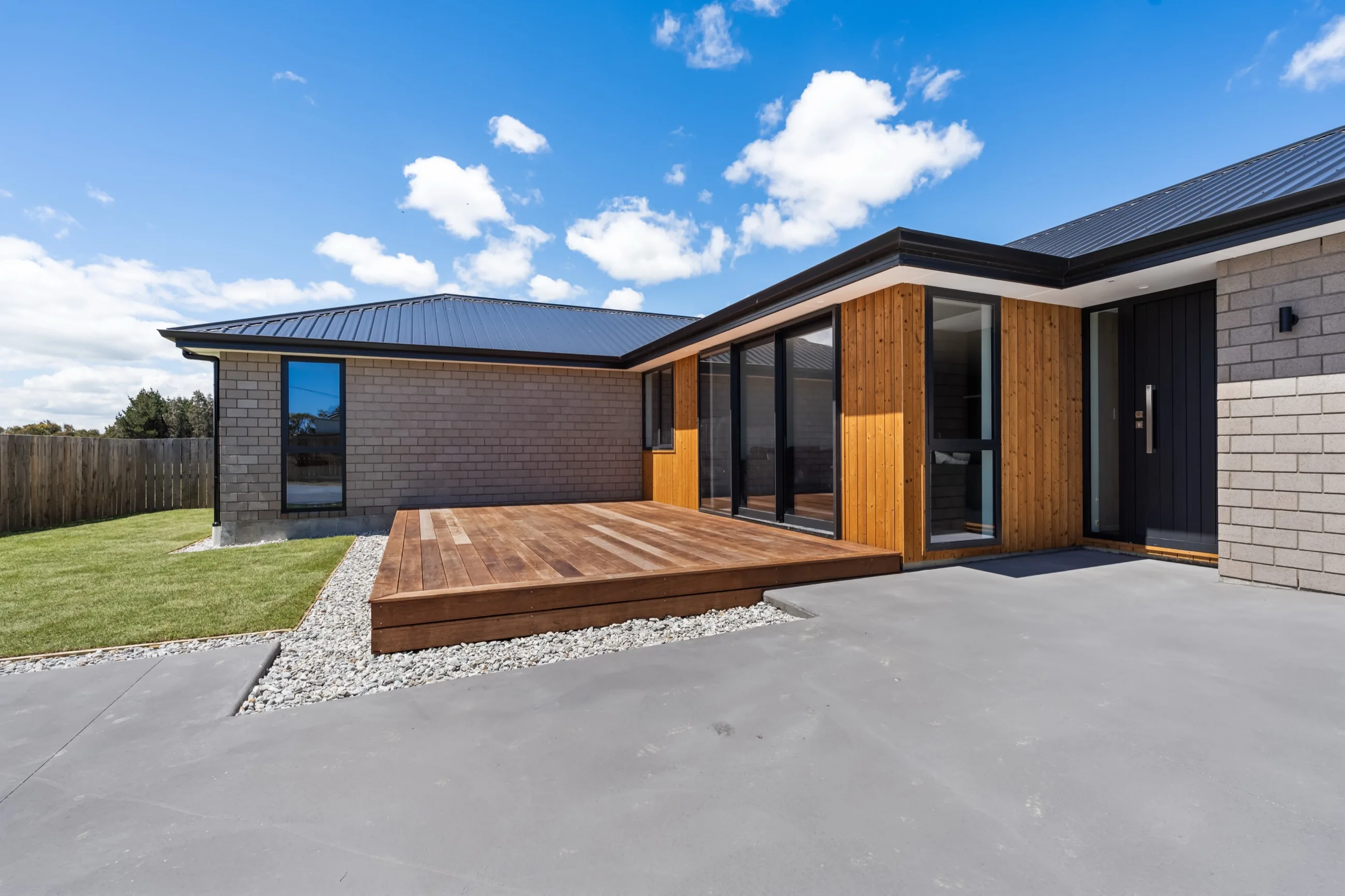 Completed Honiss Developments home with timber cladding, brick exterior, and paved driveway